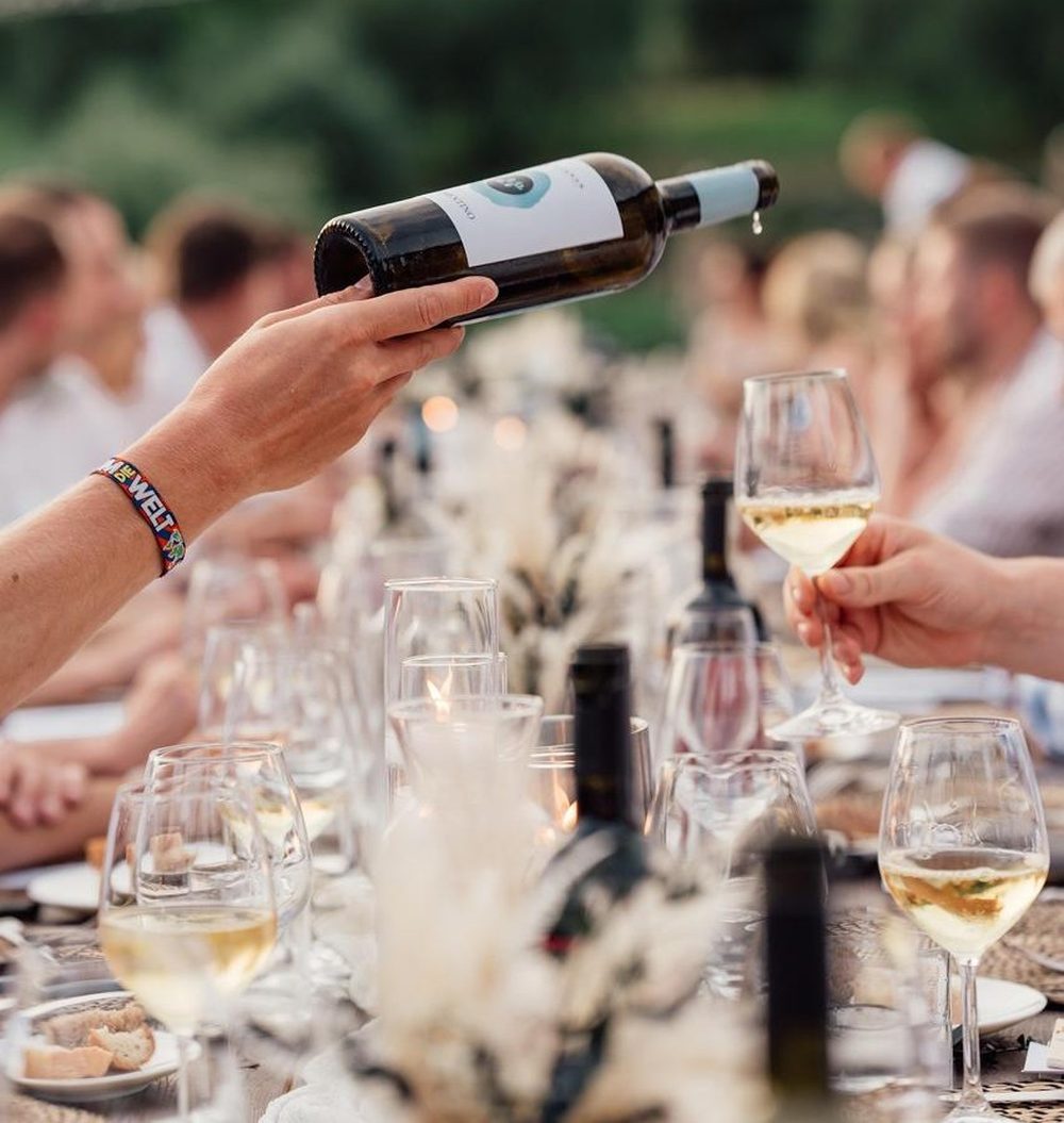 Wine being poured at a long outdoor dinner table