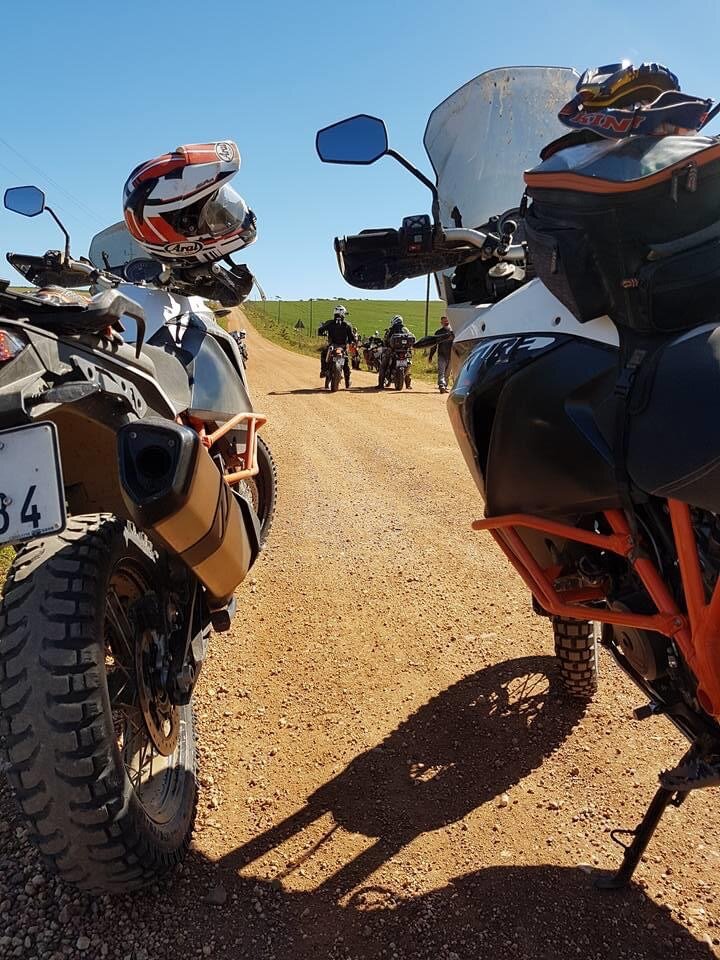 Instructor speaking with riders beside their motorcycles on a gravel road